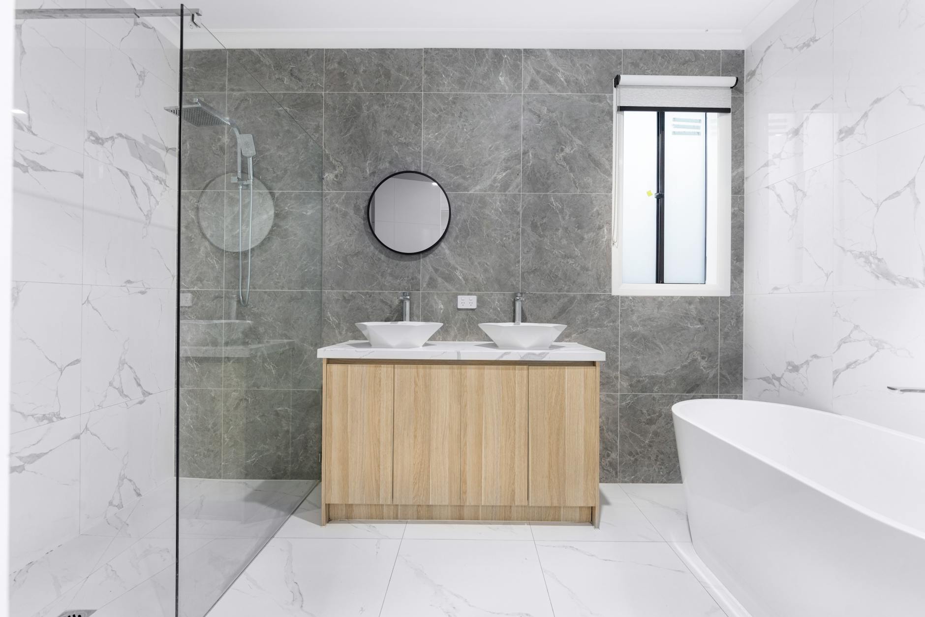 Modern bathroom remodeling reference with dual sinks, marble tile, and glass shower.