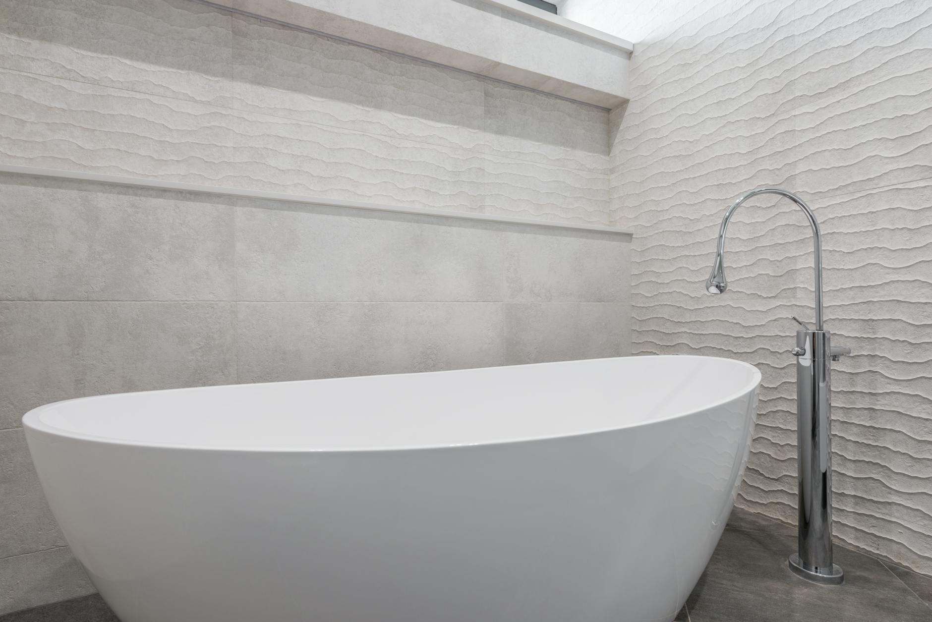 Bathroom remodel reference with stone walls, tub, and chrome faucet.