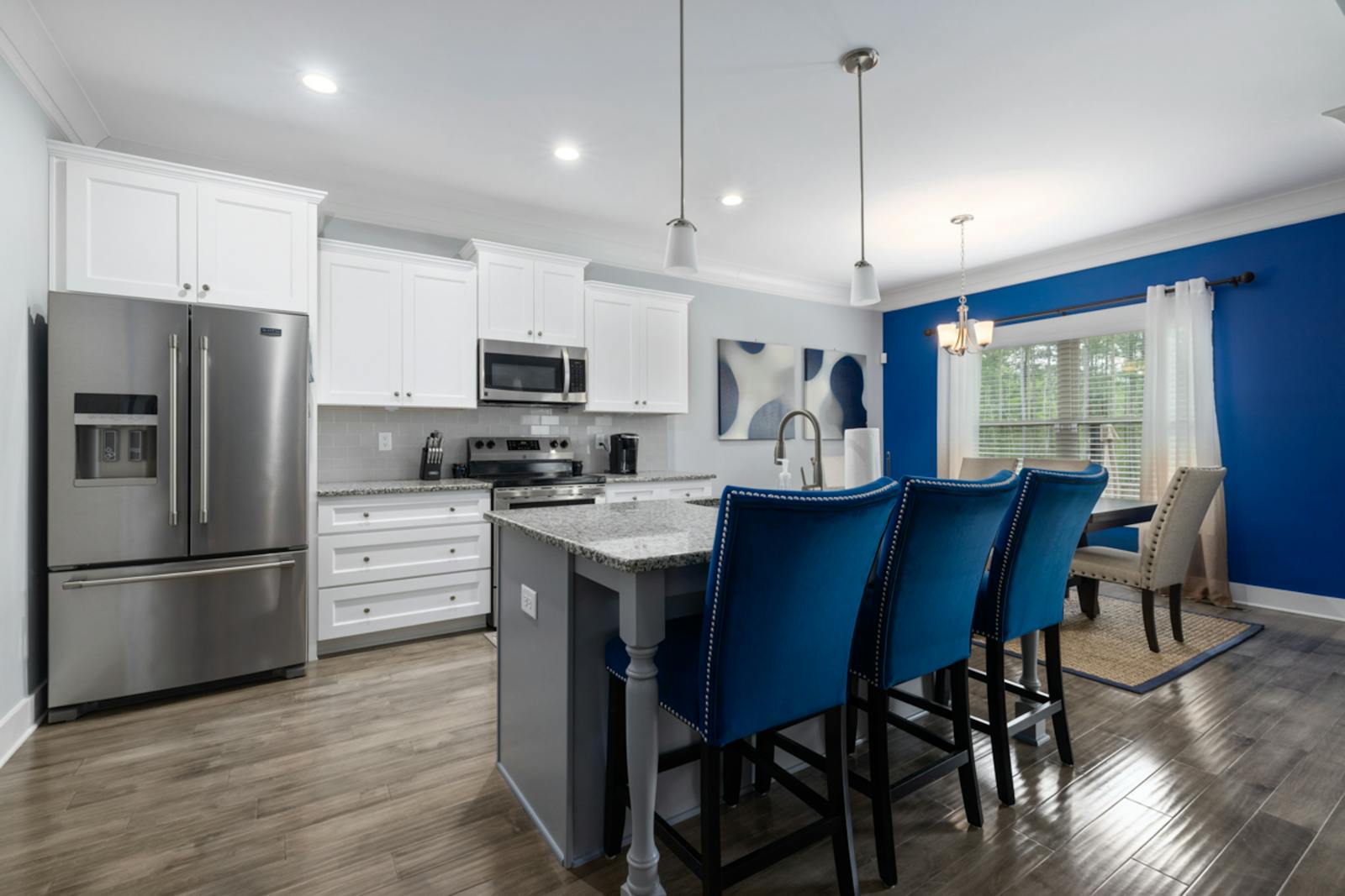 A finished modern kitchen with white cabinets, blue accents, and an island.